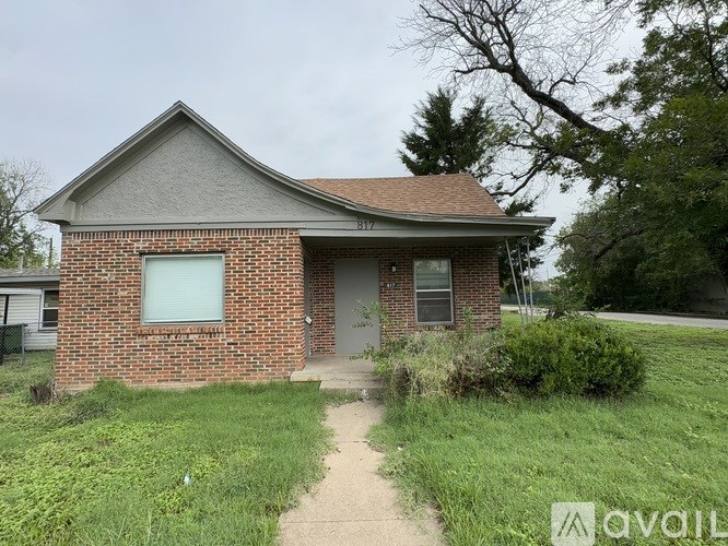 A brick house with a grey roof and a small front yard.