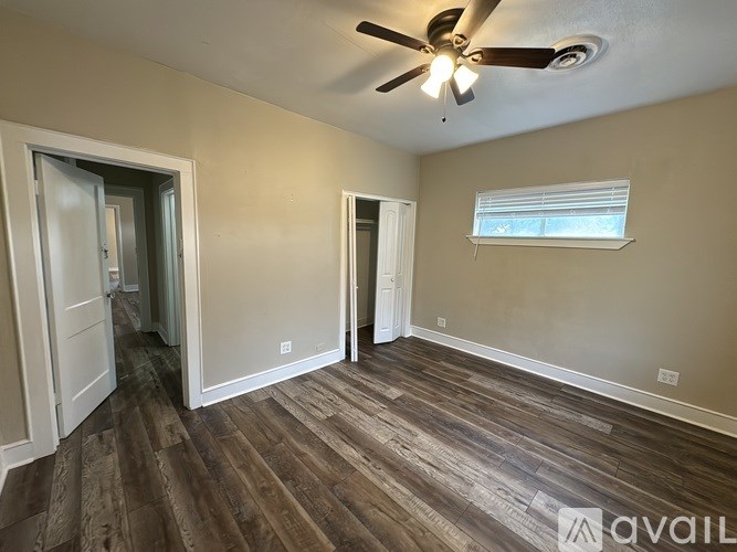 A room with a ceiling fan and wooden flooring.