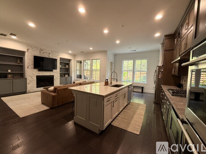 A spacious kitchen with a stone fireplace and wooden floors.