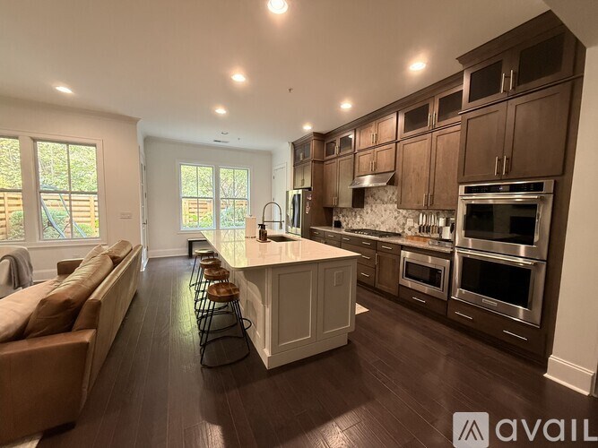 A modern kitchen with dark wood floors and stainless steel appliances.