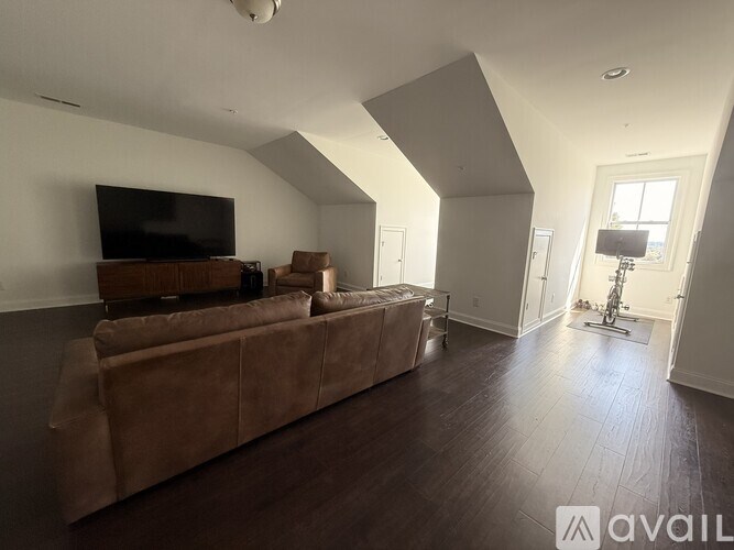 A living room with a brown couch and a television on a wooden stand.
