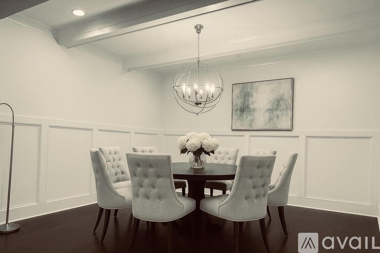A dining room with a chandelier, a table with chairs, and a painting on the wall.