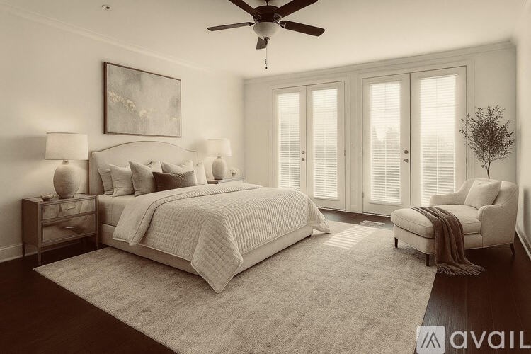 A bedroom with a large bed, a ceiling fan, and a chair.