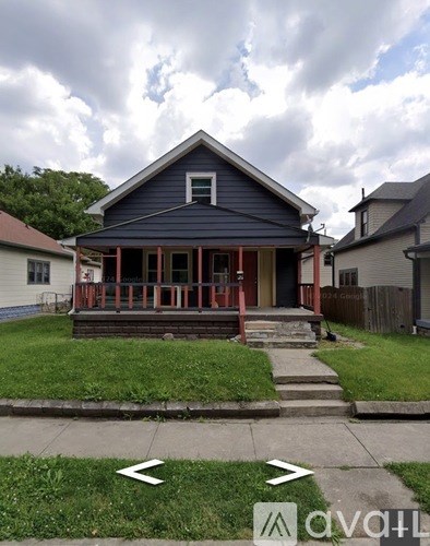A blue house with a porch and a front yard.