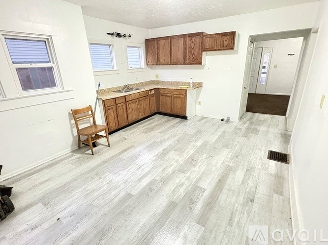 A kitchen with wooden cabinets and a grey floor.