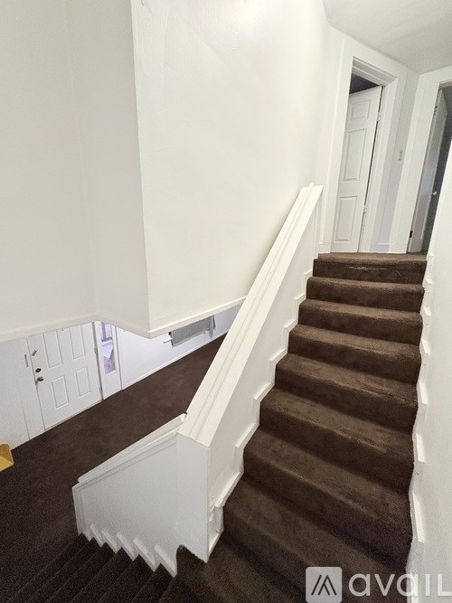 A staircase with a brown carpeted runner and white risers.