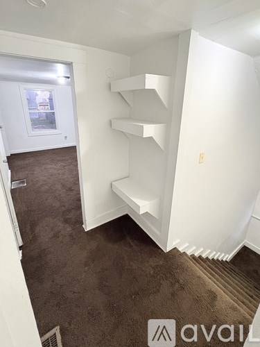 A room with a carpeted floor and a staircase with white railings.
