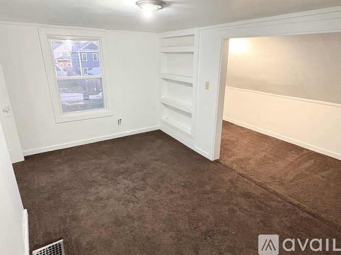 A room with a window and a carpeted floor.