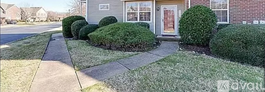 A house with a red door is surrounded by green bushes.