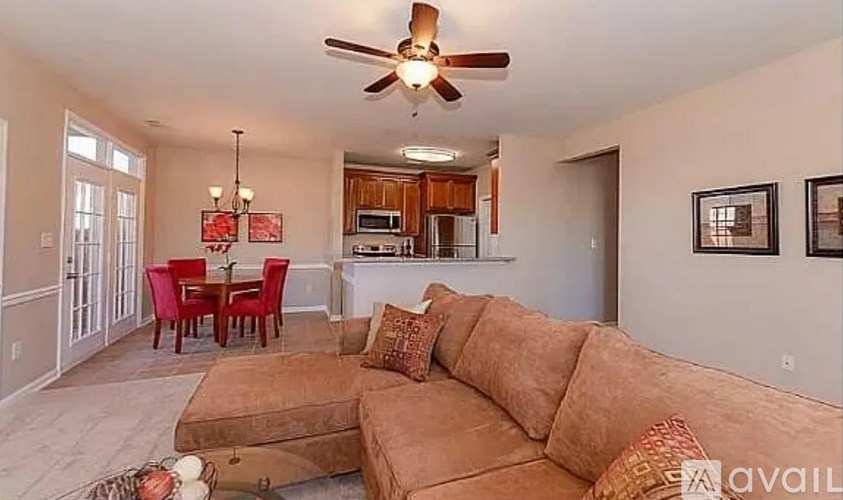 A living room with a brown couch and a ceiling fan.