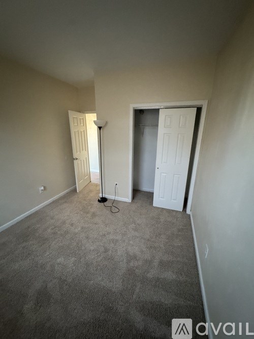A room with a carpeted floor and two doors, one of which is open.