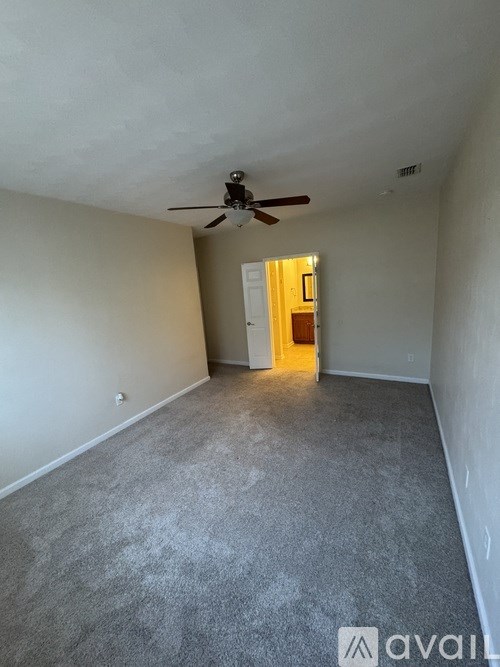 A room with a ceiling fan and carpeted floor.