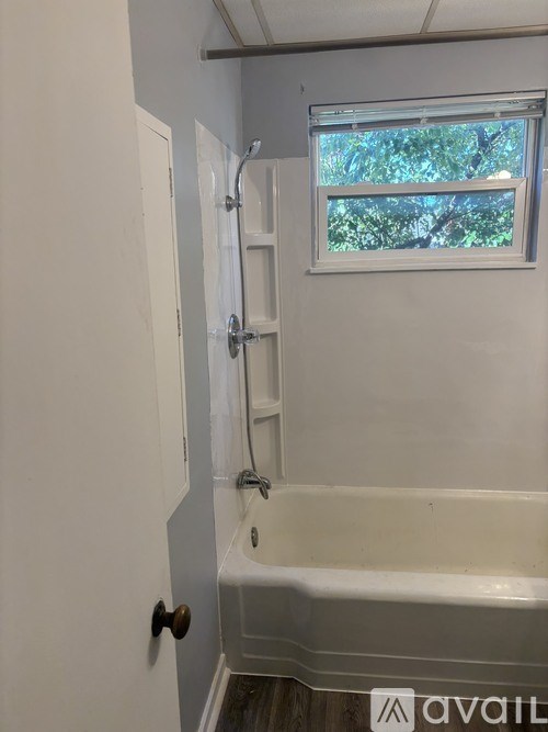 A bathroom with a white tub and a window.