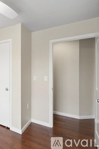 A room with a white door and a white wall with a light switch.