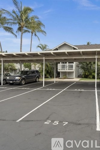 A parking lot with a car parked and a house in the background.