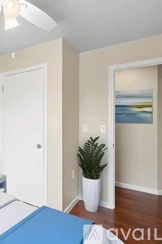 A room with a bed, a plant, and a painting on the wall.