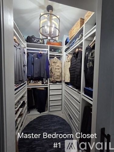 A neatly organized master bedroom closet with clothes and a chandelier.