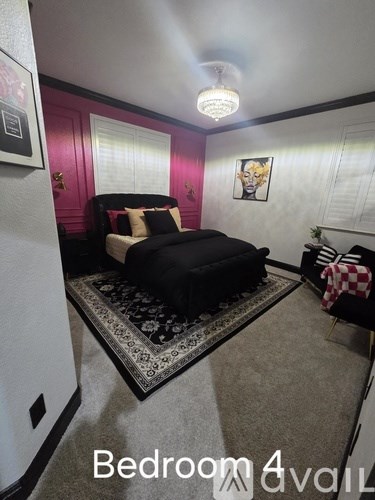 A bedroom with a black bed and a rug on the floor.