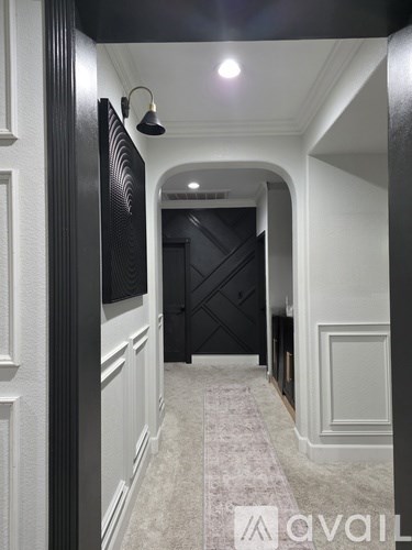 A hallway with a carpeted floor and a black door at the end.