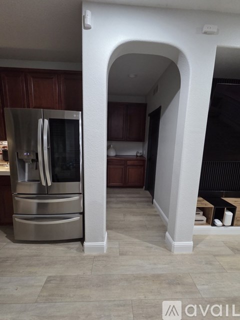 A kitchen with a stainless steel refrigerator and wooden cabinets.
