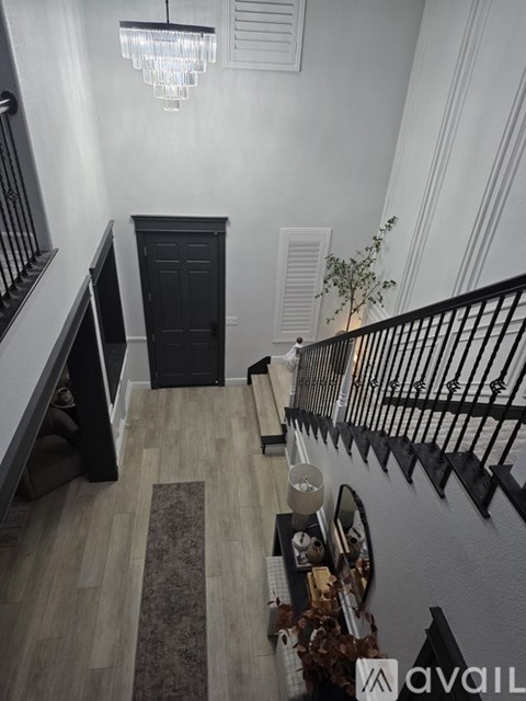 A hallway with a black door and a chandelier.