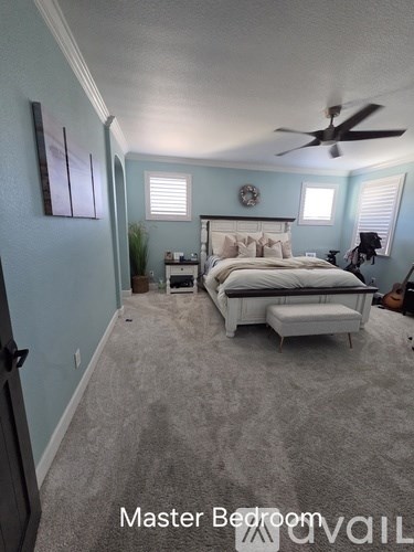 A master bedroom with a bed, dresser, and ceiling fan.