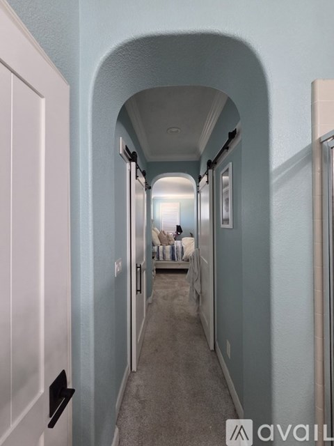 A hallway with a white door on the left and a white wall on the right.