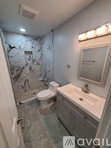 A bathroom with a marble patterned shower and a white toilet.
