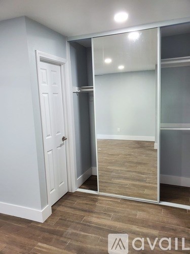 A room with a white door and a mirrored wall.