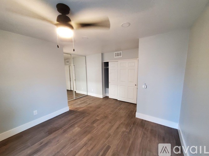 A room with a ceiling fan and wooden flooring.