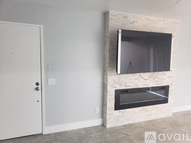 A white door is open to a room with a stone fireplace.