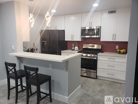 A kitchen with a white island and black chairs.
