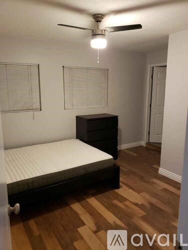 A bedroom with a bed, dresser, and a ceiling fan.