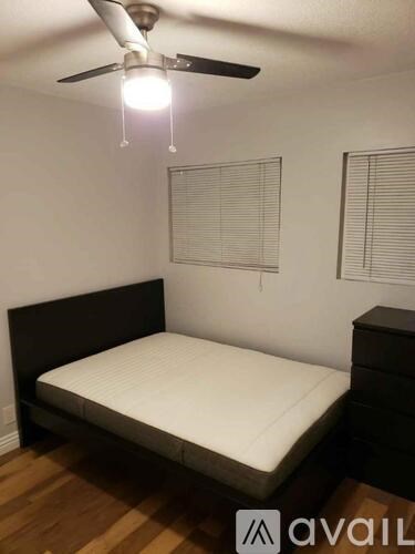 A bedroom with a bed, dresser, and ceiling fan.