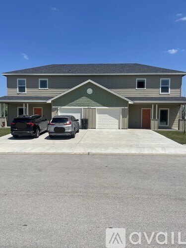 Two cars are parked in front of a two-story house.