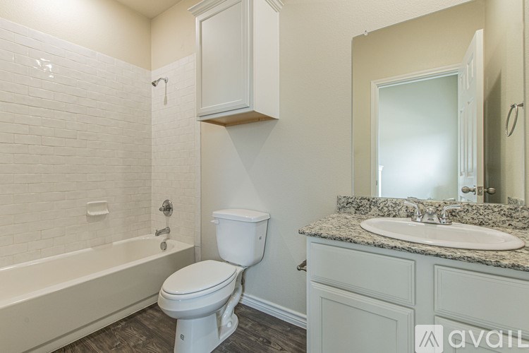 A white toilet in a bathroom with a white tub and a white sink.