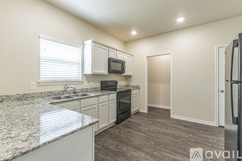 A kitchen with granite countertops and white cabinets.