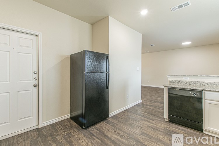 A black fridge in a room with a white door and a fireplace.