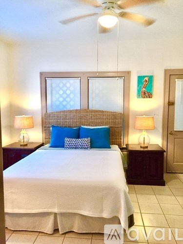 A bedroom with a bed, two lamps, and a ceiling fan.