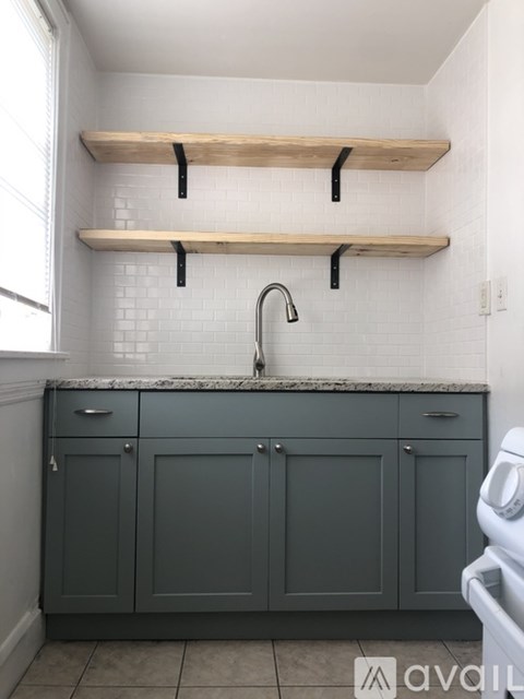 A kitchen with grey cabinets and a white sink.