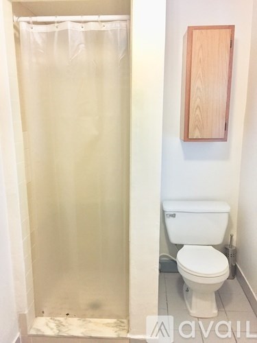 A white toilet in a small bathroom with a wooden framed mirror above it.