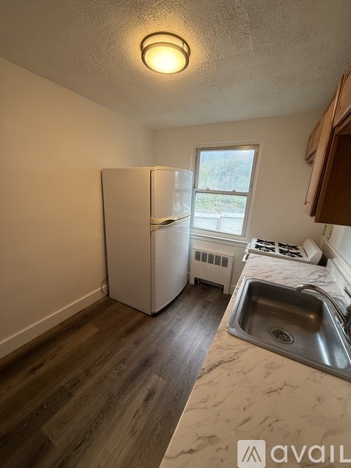 A kitchen with a white fridge, sink, and wood floors.
