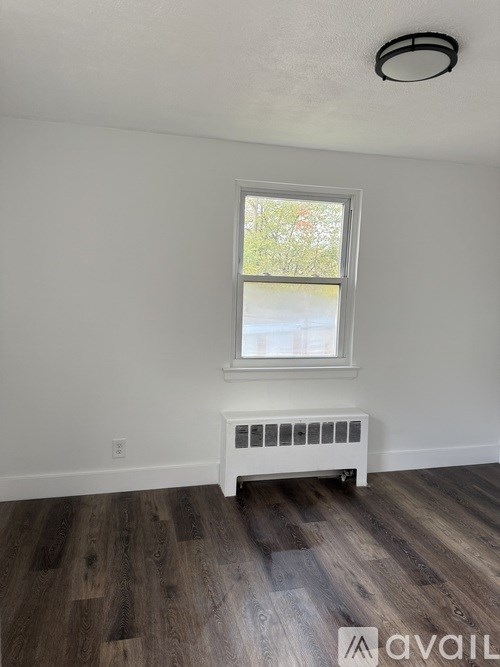 A room with a window and a radiator on the floor.