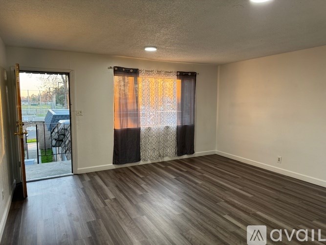 A room with wooden flooring and a sliding glass door leading to a patio.