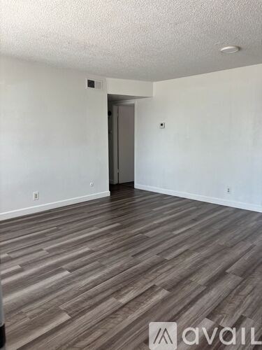 A room with wooden flooring and a doorway leading to another room.