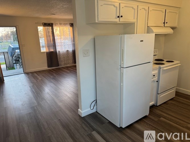 A kitchen with a white fridge and wooden floors.