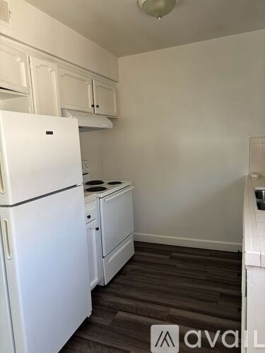 A white fridge in a kitchen with wooden floors.