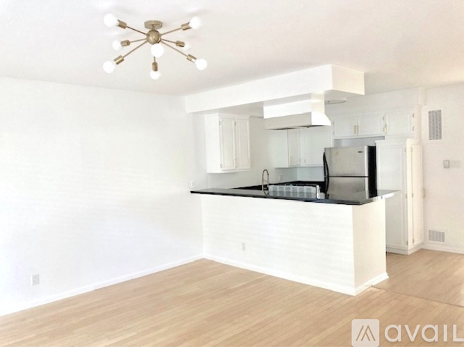 A kitchen with white cabinets and a black countertop is available for rent.