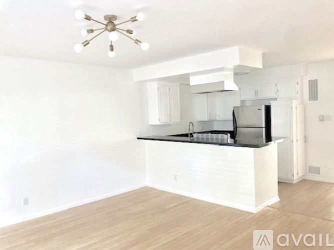 A kitchen with white cabinets and a black countertop is available for rent.