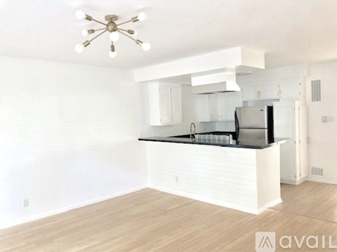 A kitchen with white cabinets and a black countertop is available for rent.